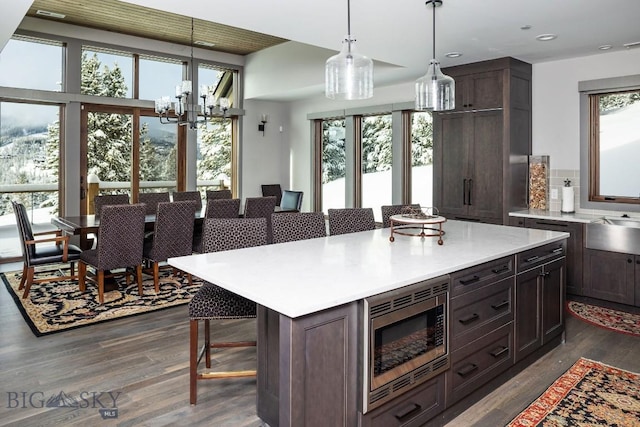 13 Middle Rider, Big Sky, MT 59716 - kitchen with stainless steel microwave, a breakfast bar area, dark wood-type flooring, light countertops, and a chandelier