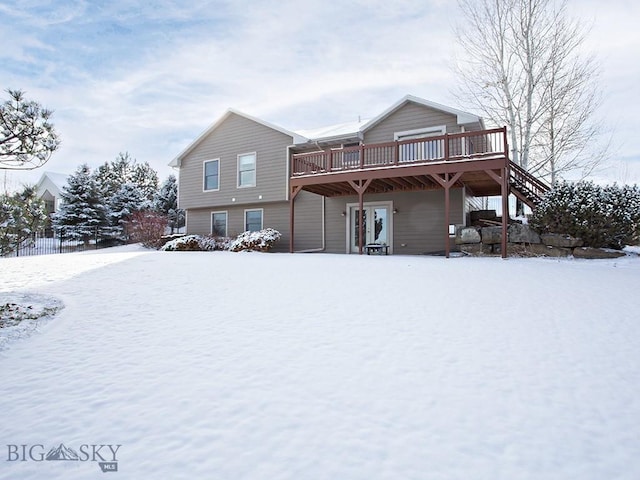 snow covered back of property featuring a wooden deck