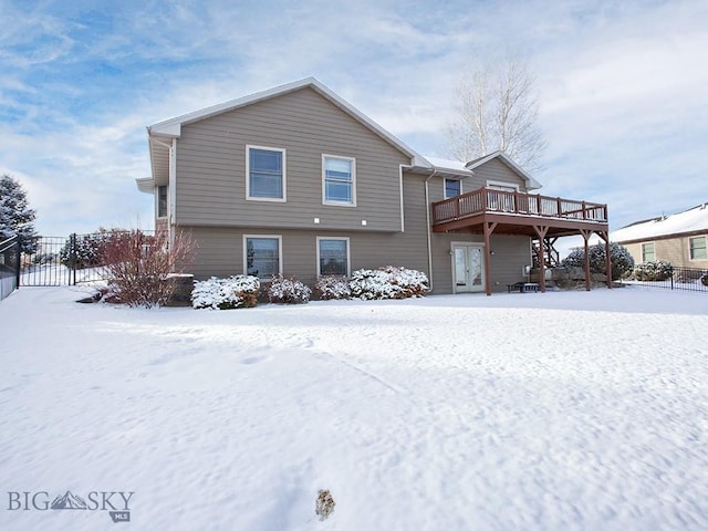 snow covered house featuring a wooden deck