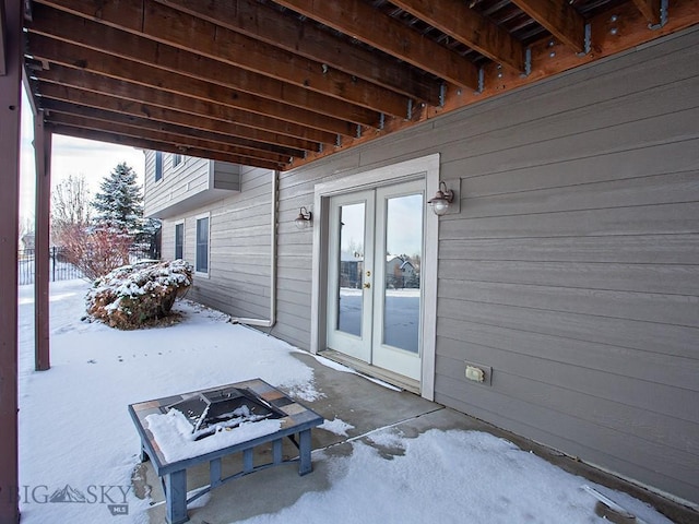 snow covered patio featuring french doors and a fire pit