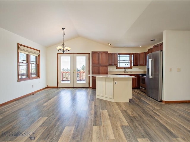 kitchen featuring a center island, stainless steel appliances, wood-type flooring, vaulted ceiling, and decorative light fixtures