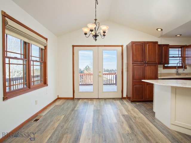 kitchen with a wealth of natural light, hanging light fixtures, lofted ceiling, and light wood-type flooring