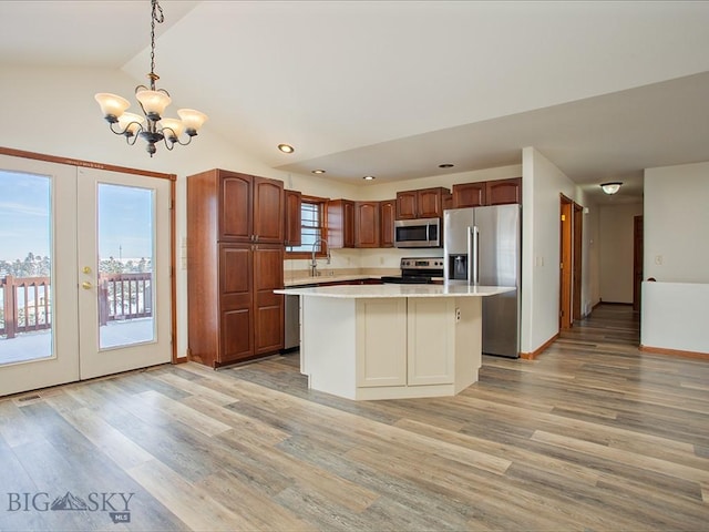 kitchen with light wood-type flooring, stainless steel appliances, a center island, hanging light fixtures, and lofted ceiling