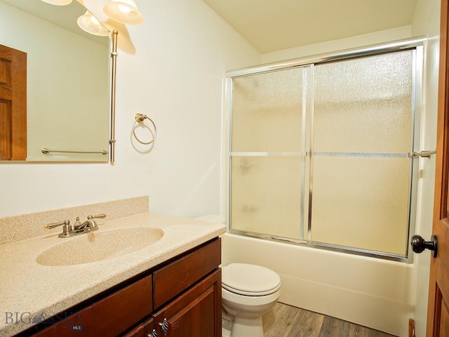 full bathroom with hardwood / wood-style flooring, vanity, toilet, and bath / shower combo with glass door