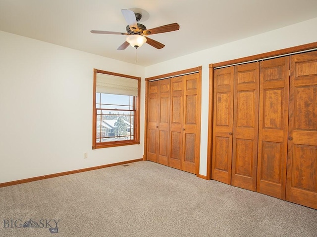 unfurnished bedroom featuring light carpet, two closets, and ceiling fan