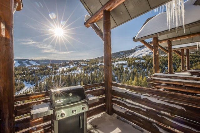 snow covered patio featuring a mountain view and area for grilling