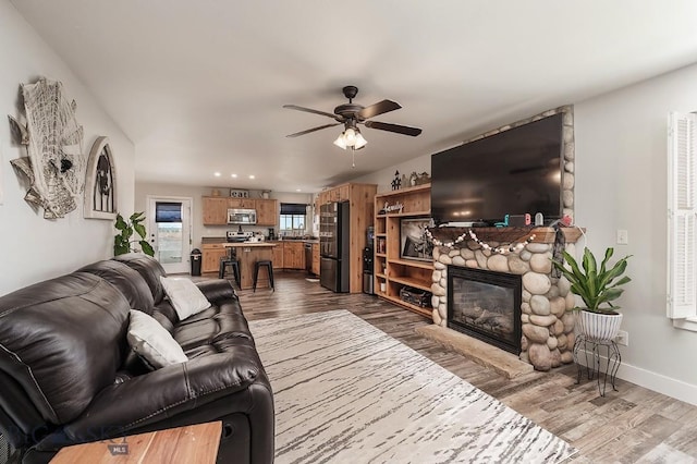 living room featuring ceiling fan, a fireplace, and wood-type flooring