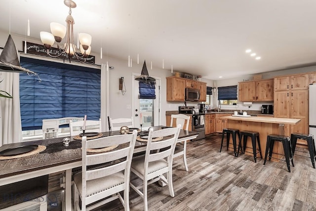 dining space with sink, a notable chandelier, and light hardwood / wood-style flooring