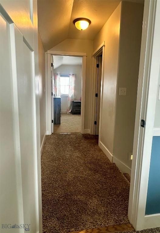 hallway featuring carpet flooring and vaulted ceiling