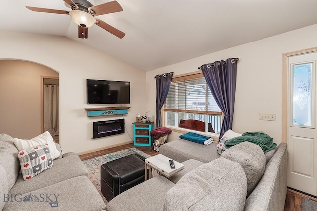 1191 Chipper Ln, Huntley, MT 59037 - living room featuring arched walkways, lofted ceiling, a glass covered fireplace, ceiling fan, and wood finished floors