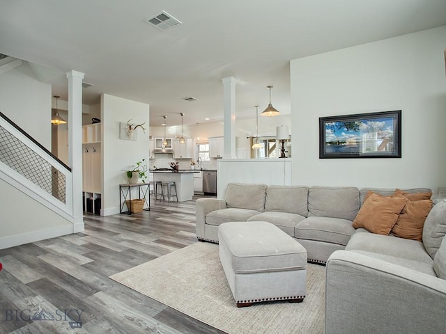 living room with sink, hardwood / wood-style floors, and ornate columns