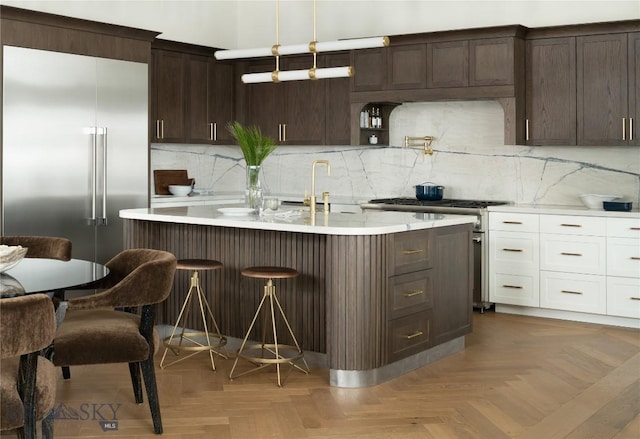 kitchen featuring white cabinetry, parquet flooring, pendant lighting, decorative backsplash, and high end appliances