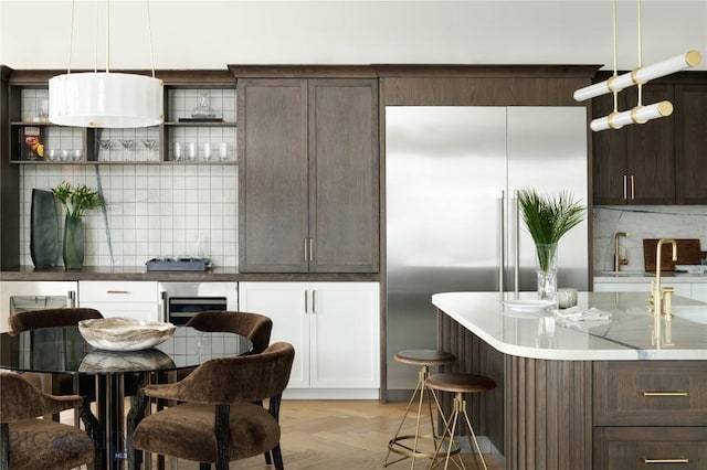 kitchen with backsplash, dark brown cabinets, light parquet floors, and pendant lighting