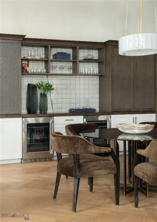 interior space featuring a large fireplace, beverage cooler, ventilation hood, light parquet floors, and dark brown cabinets