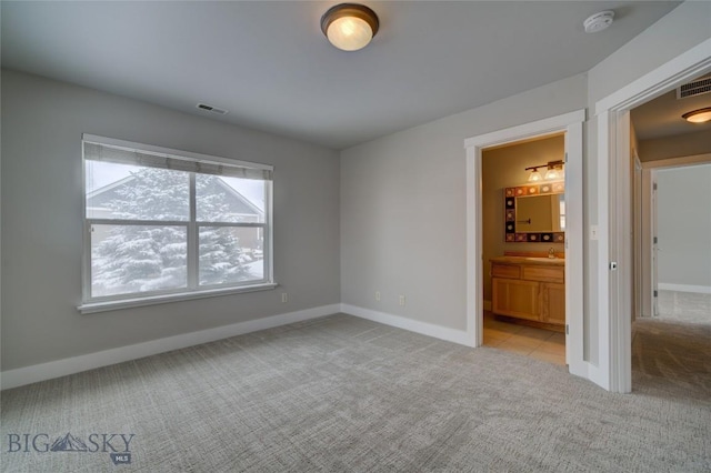 unfurnished bedroom with connected bathroom, sink, and light colored carpet