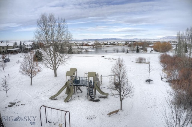 yard covered in snow featuring a playground and a mountain view