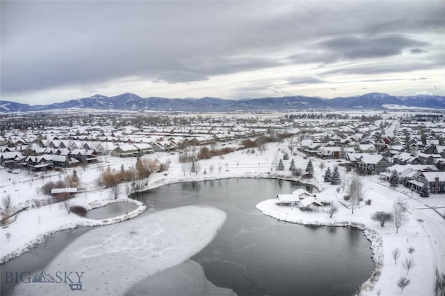 snowy aerial view featuring a water and mountain view