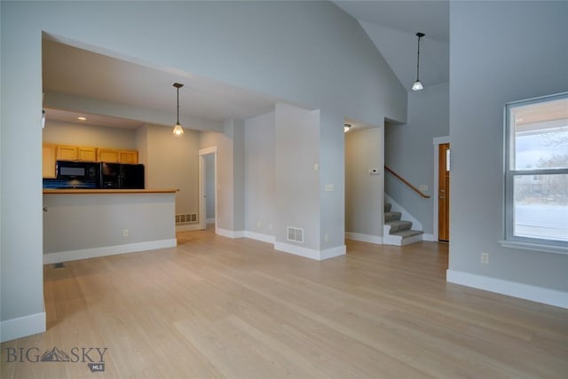 unfurnished living room with high vaulted ceiling and light hardwood / wood-style flooring