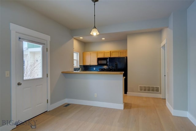 kitchen featuring hanging light fixtures, kitchen peninsula, light brown cabinetry, black appliances, and light wood-type flooring