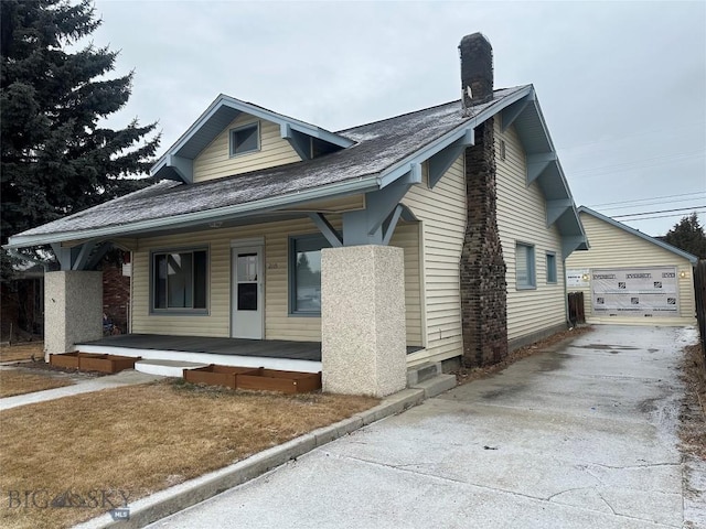 bungalow with covered porch, an outbuilding, and a garage