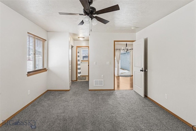 unfurnished bedroom with a textured ceiling, carpet, and ceiling fan with notable chandelier