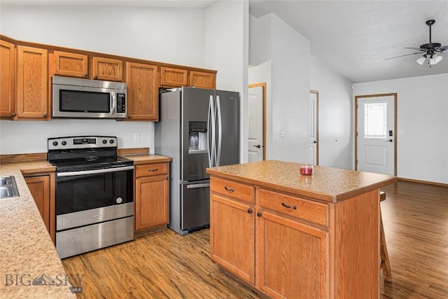 kitchen featuring ceiling fan, a center island, stainless steel appliances, and lofted ceiling