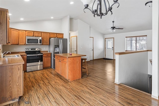 kitchen with dark wood-type flooring, sink, decorative light fixtures, a kitchen island, and stainless steel appliances