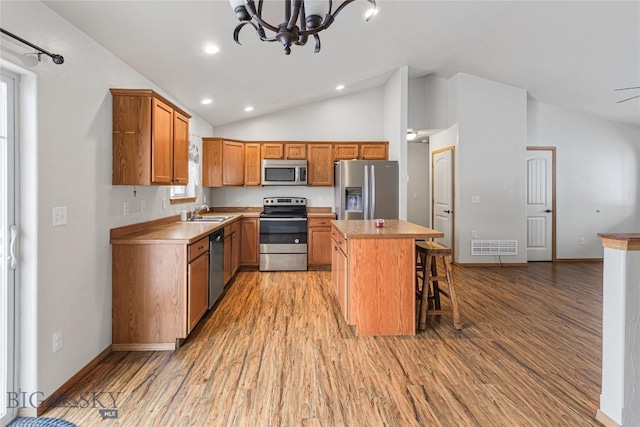 kitchen with a kitchen bar, appliances with stainless steel finishes, sink, a center island, and light hardwood / wood-style floors