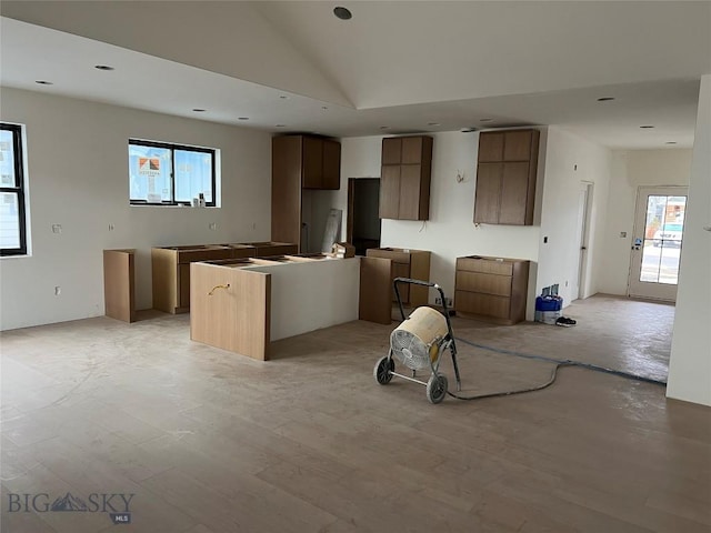 kitchen featuring high vaulted ceiling, a kitchen island, a wealth of natural light, and light hardwood / wood-style flooring