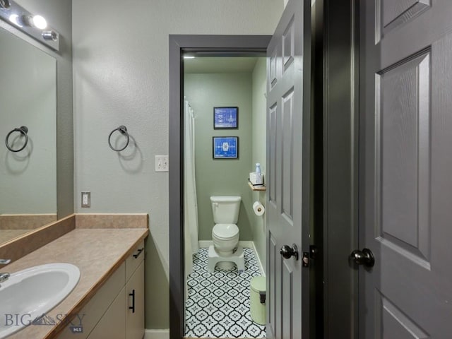 bathroom with a shower with curtain, vanity, toilet, and tile patterned floors