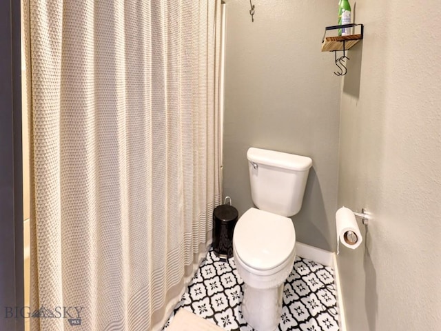 bathroom featuring toilet and curtained shower