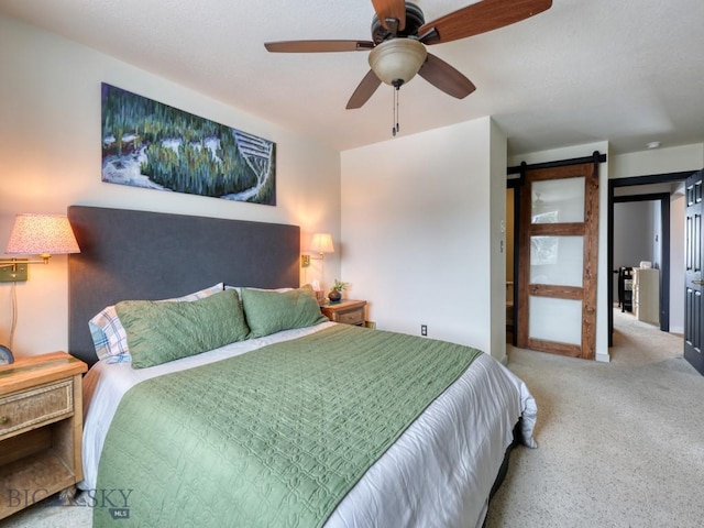 bedroom with ceiling fan and a barn door