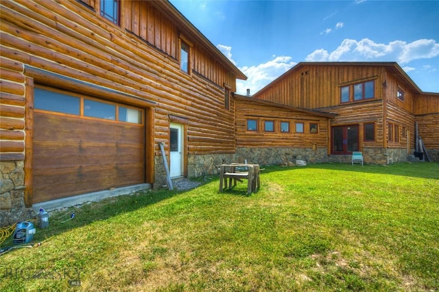 rear view of property with a garage and a yard