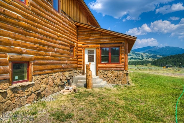 doorway to property with a mountain view and a lawn