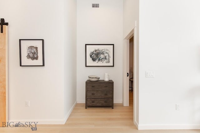 corridor featuring a barn door and light hardwood / wood-style floors