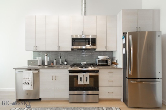 kitchen featuring light wood-type flooring, sink, appliances with stainless steel finishes, and tasteful backsplash