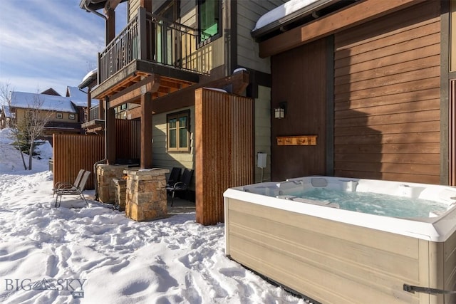 snow covered property with a balcony and a hot tub