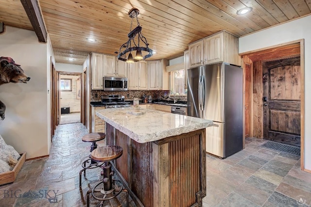 kitchen featuring light stone countertops, appliances with stainless steel finishes, a kitchen bar, pendant lighting, and a center island