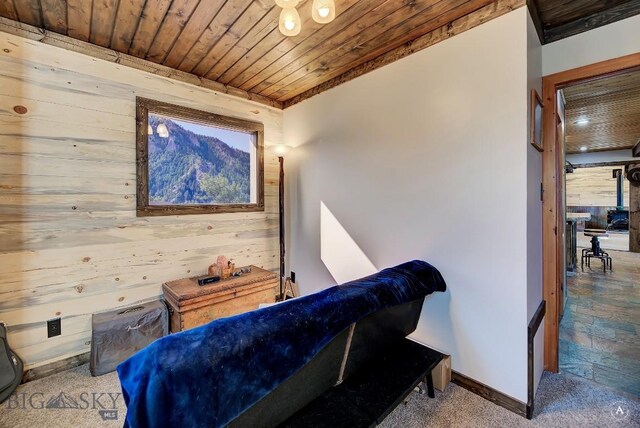 bedroom with carpet flooring, wood walls, and wooden ceiling