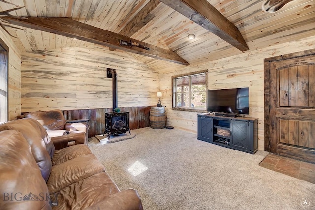 living room with vaulted ceiling with beams, light colored carpet, a wood stove, and wooden walls