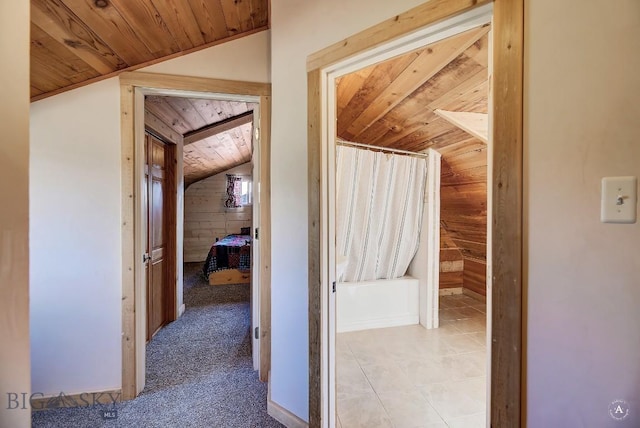 hallway with wood ceiling, lofted ceiling, and wooden walls