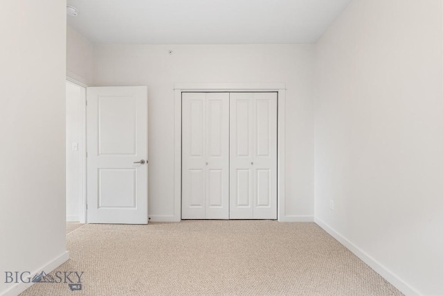 unfurnished bedroom with a closet, carpet, and baseboards