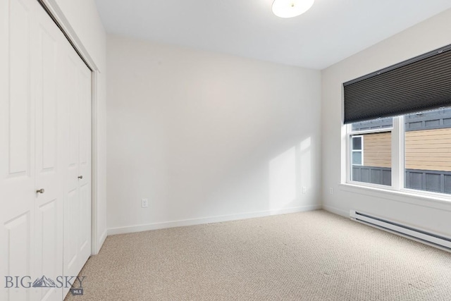 unfurnished bedroom with light carpet, a baseboard radiator, baseboards, and a closet