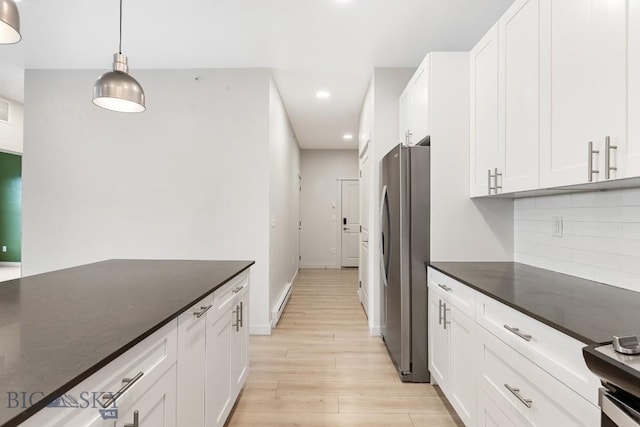 kitchen featuring white cabinetry, light wood-type flooring, freestanding refrigerator, tasteful backsplash, and dark countertops