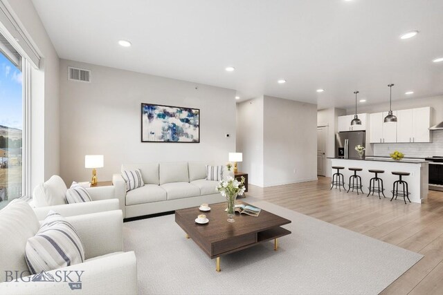 living area with light wood-type flooring, visible vents, and recessed lighting