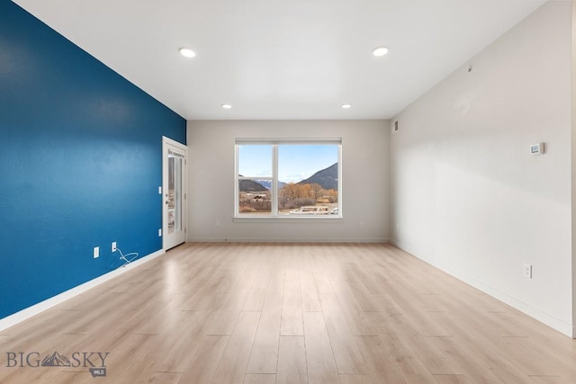 empty room featuring light wood-type flooring, baseboards, and recessed lighting