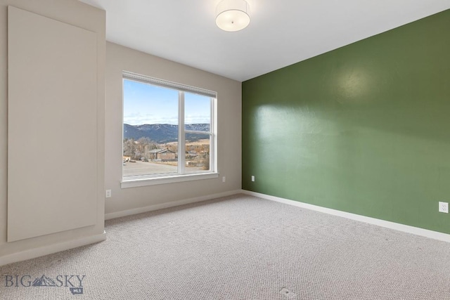 empty room featuring lofted ceiling, carpet, and baseboards