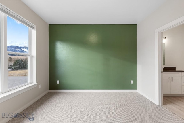 spare room featuring light carpet and baseboards