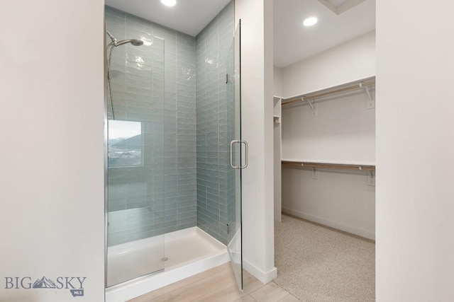 bathroom with recessed lighting, a shower stall, baseboards, and a spacious closet