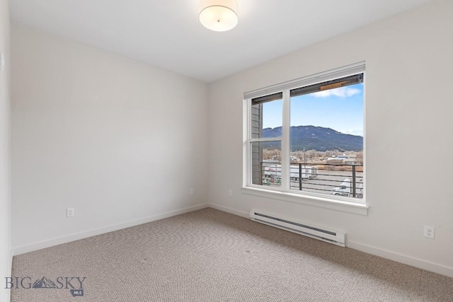 carpeted spare room with a baseboard heating unit, a mountain view, and baseboards